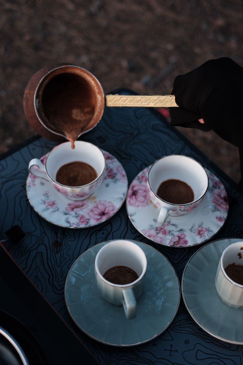 Aesthetic pour of Turkish coffee into elegant floral cups. Perfect for cozy outdoor gatherings.
