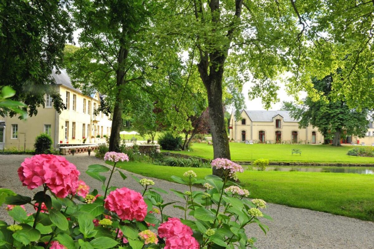 Elegant European country estate with yellow manor houses, lush green lawns, and vibrant pink hydrangeas.