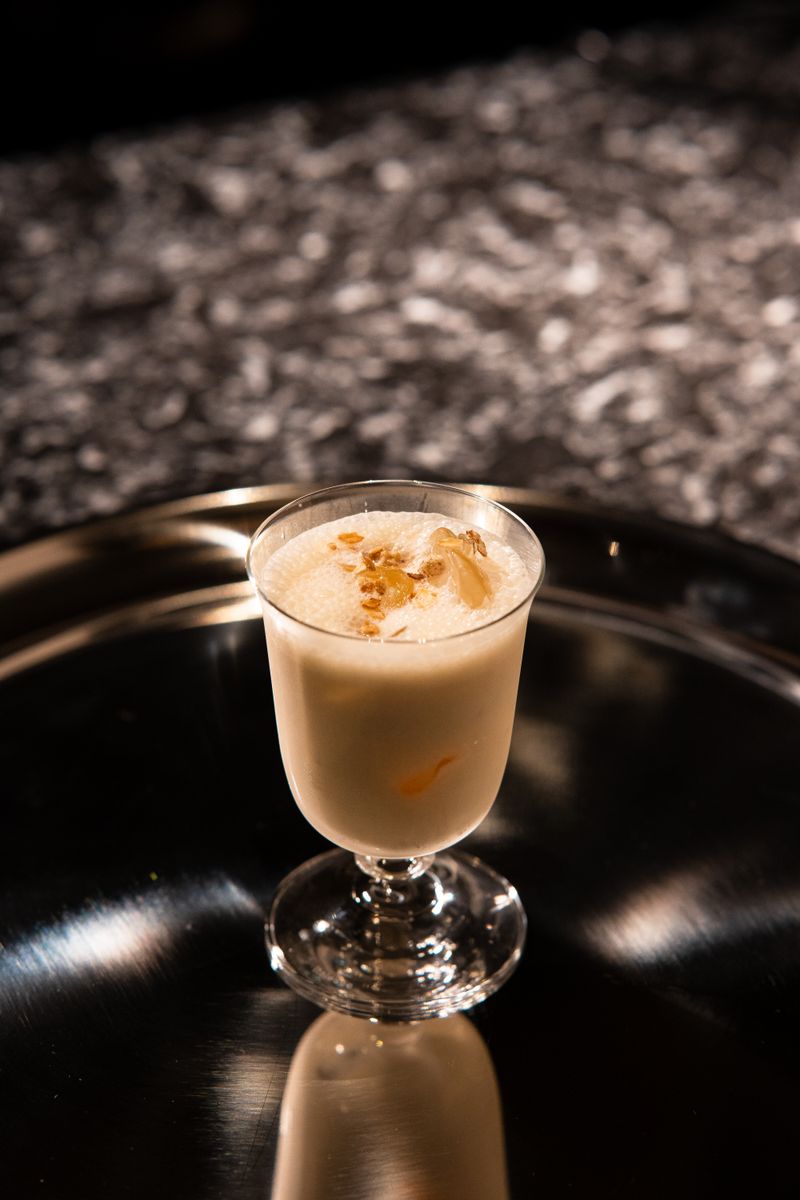 A creamy cocktail in an elegant glass on a reflective tray, perfect for bar settings.