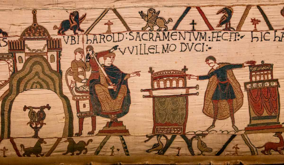 Embroidered textile panel featuring figures, Latin text, and stylized animals in a medieval artistic style.