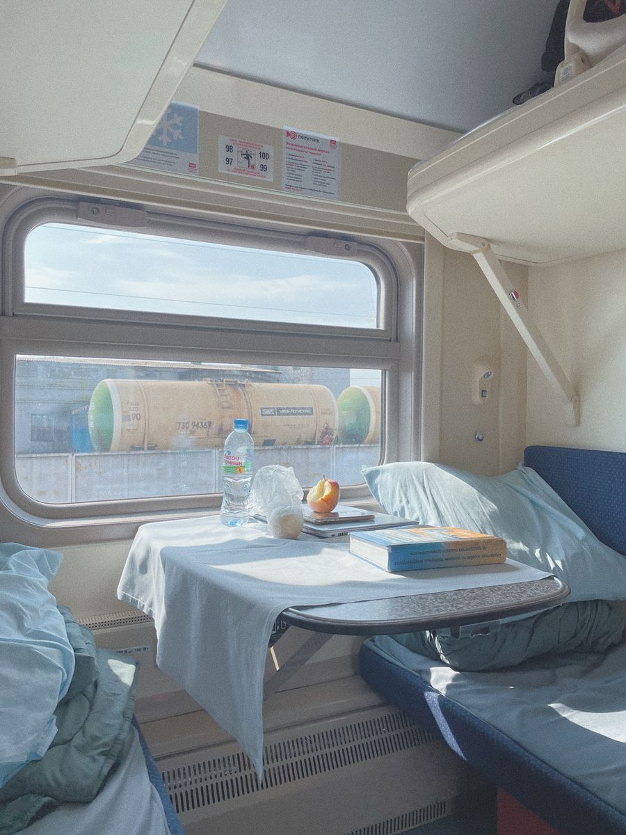 Sunlit train cabin interior with a view of the passing landscape, depicting travel comfort.