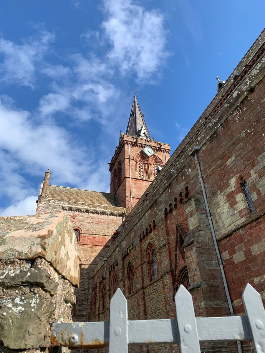 The historic St. Magnus Cathedral in Kirkwall against a vivid blue sky, showcasing its medieval architecture.