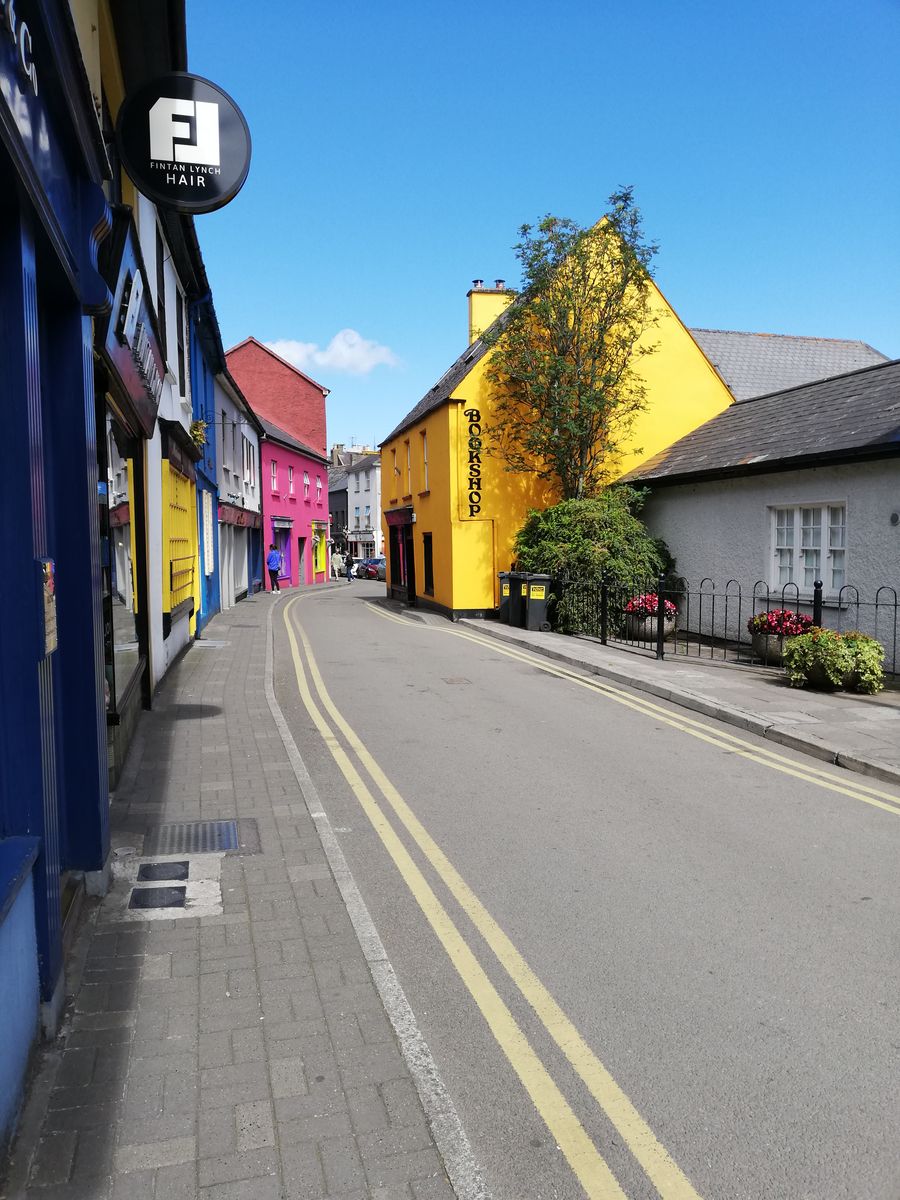 Vibrant, colorful street view in Kinsale, Ireland featuring historic architecture and a sunny atmosphere.