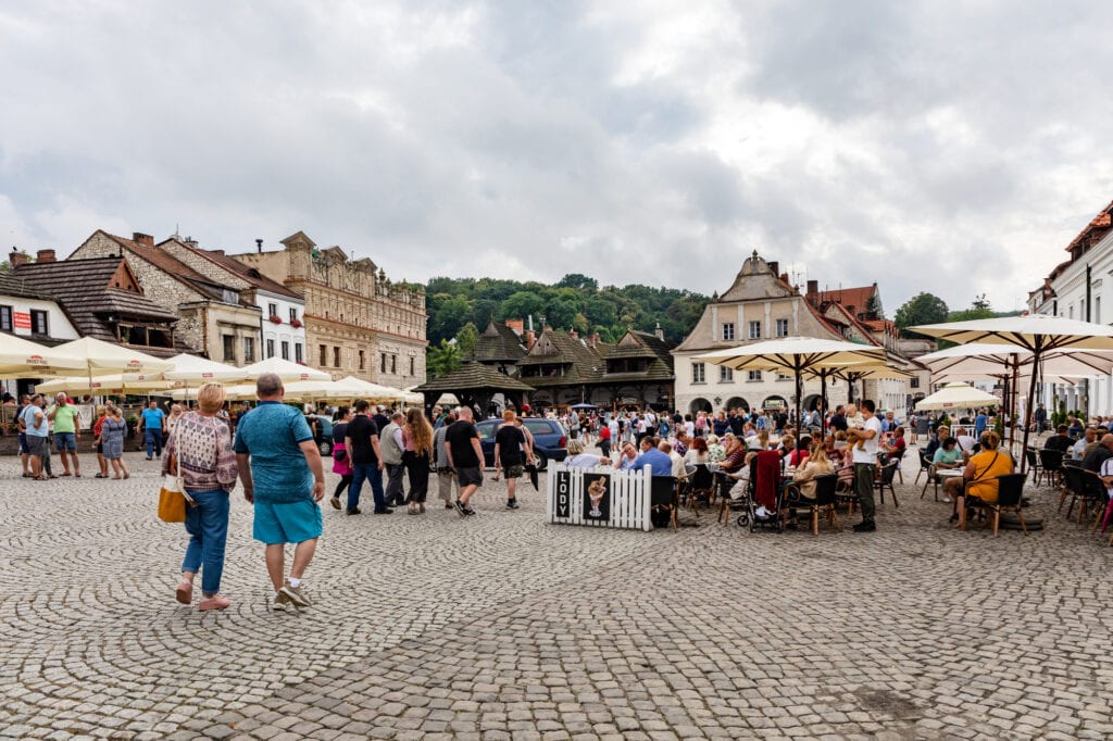 KAZIMIERZ DOLNY, POLAND - AUGUST 23, 2020: Tourists in the old town square. Visible renaissance townhouses of St. Christopher and St. Nicholas.