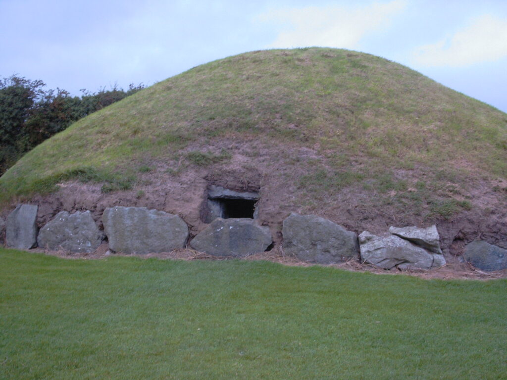 A close view of the green mound with an entry cut out and surrounded by stones