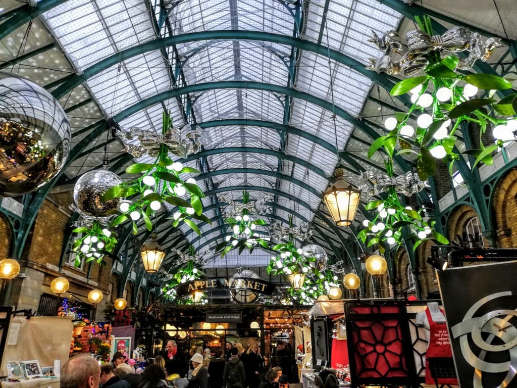 The Apple Market at Covent Garden market with its glass domed roof and large hanging Christmas decorations