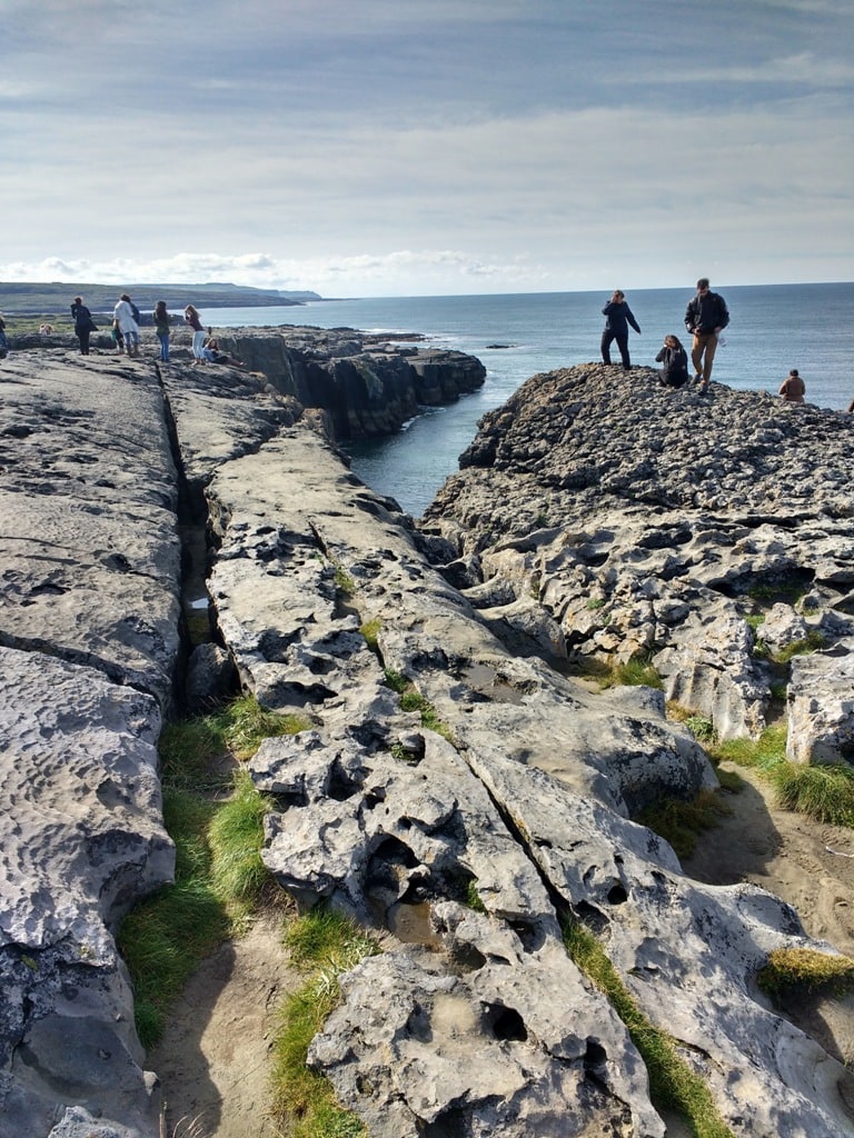 Tourists standing at the edge of the moonscape known as the Burren in Ireland