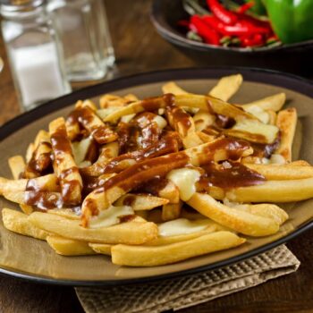 A plate of delicious poutine with french fries, gravy, and cheese curd.