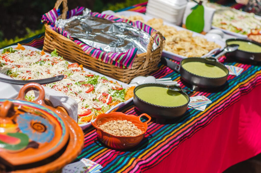 Table of Mexican Buffet with tacos enchiladas chalupas and tamales on a sunny day